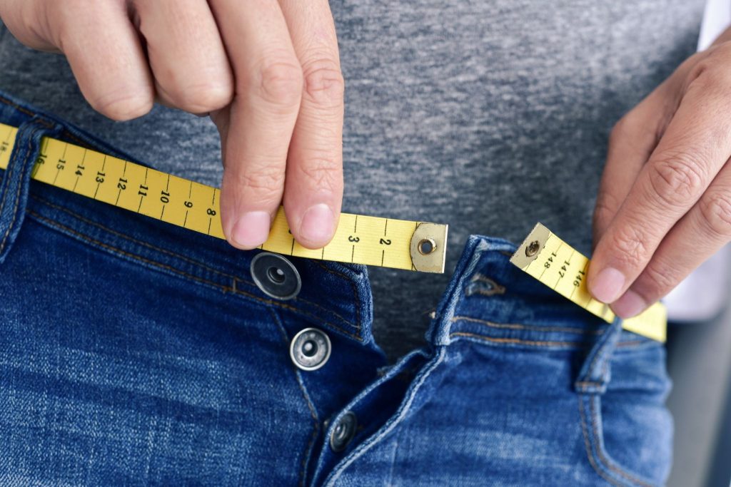 Mengukur lingkar pinggang celana jeans dengan pita ukur
