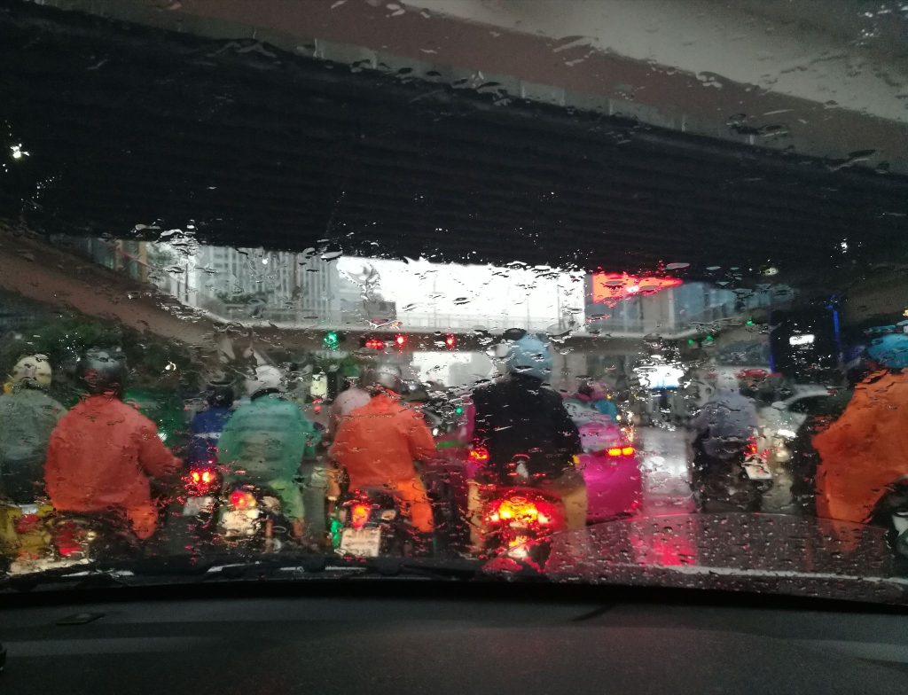 Pengendara motor di jalan saat hujan terlihat dari balik kaca mobil