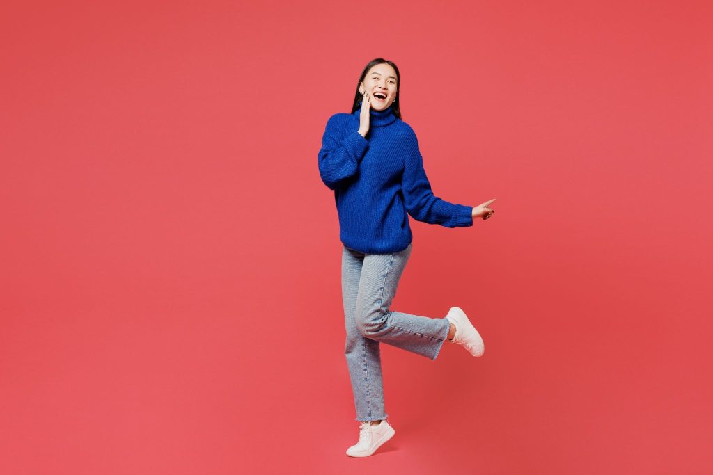 Wanita memakai sweater rajut biru berlatar merah