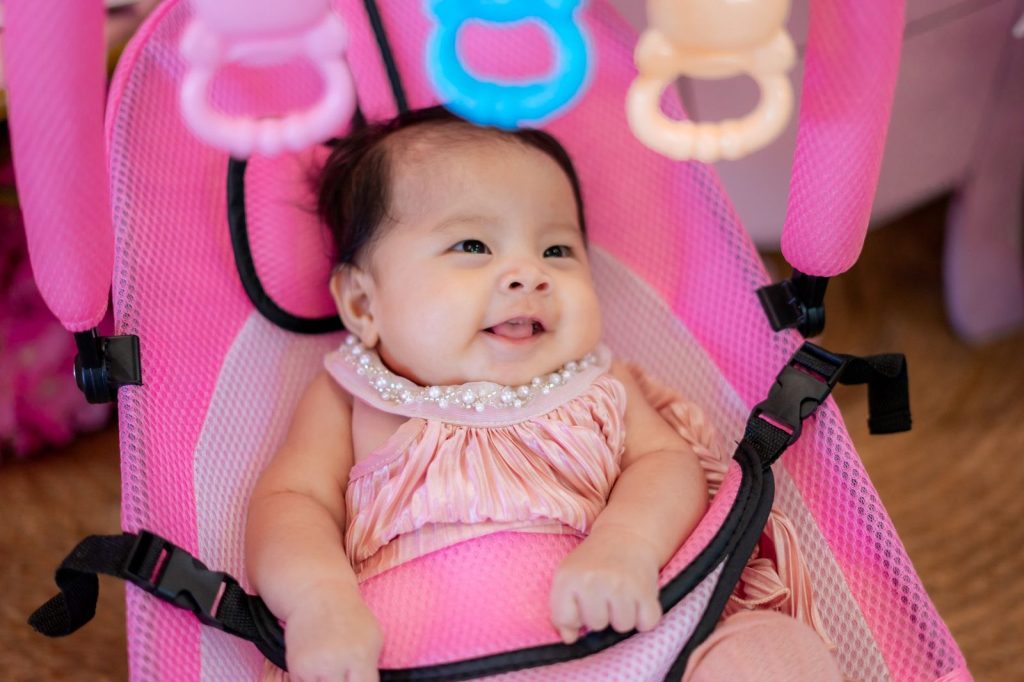 Bayi tersenyum di bouncer bayi