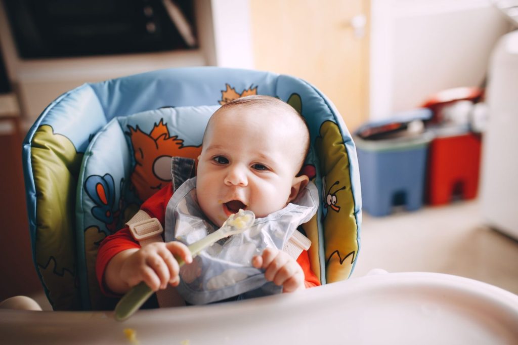 Bayi makan bubur MPASI di kursi makan