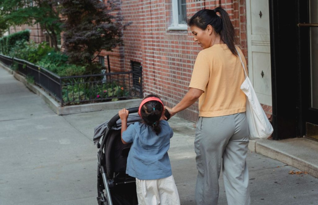 Ibu membawa tas dan stroller saat bepergian bersama anak