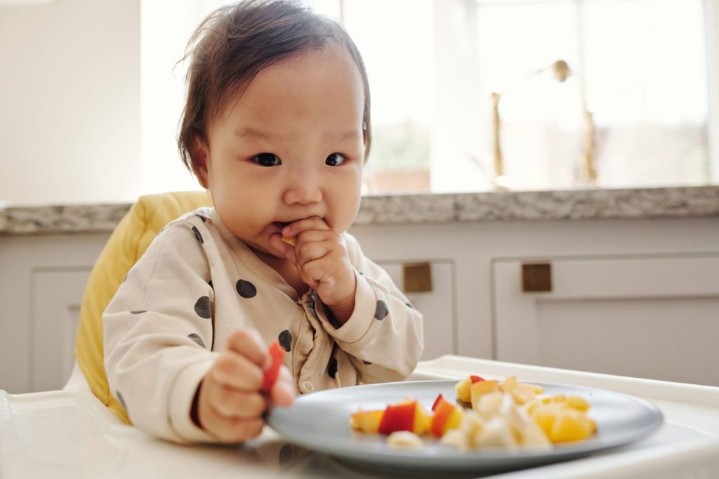 Bayi makan sendiri di kursi makan bayi