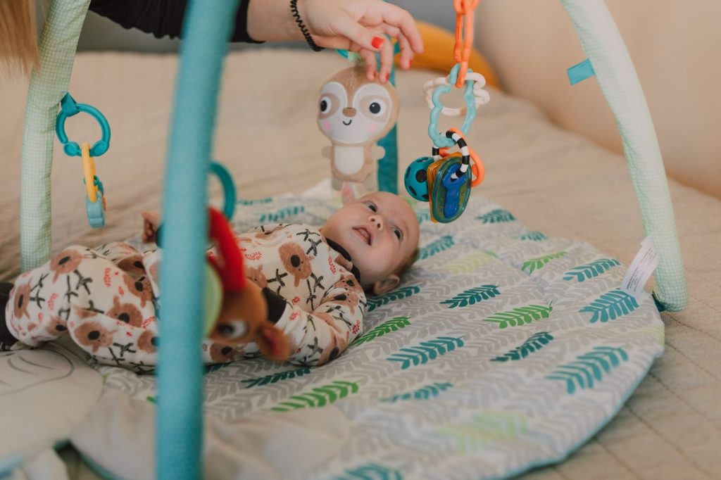 Bayi bermain di playmat dengan mainan gantung