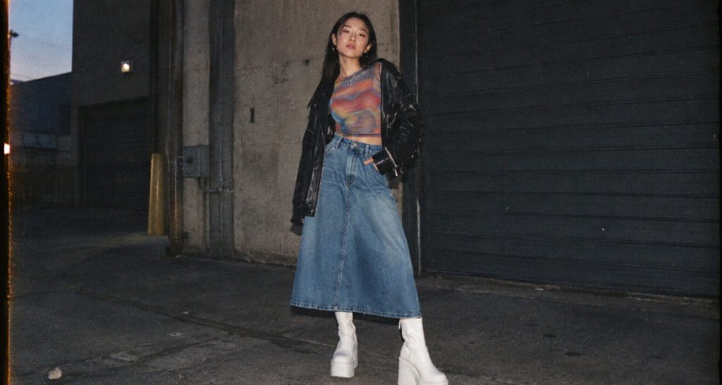 Rok payung denim dipadukan jaket kulit hitam dan sepatu boots putih