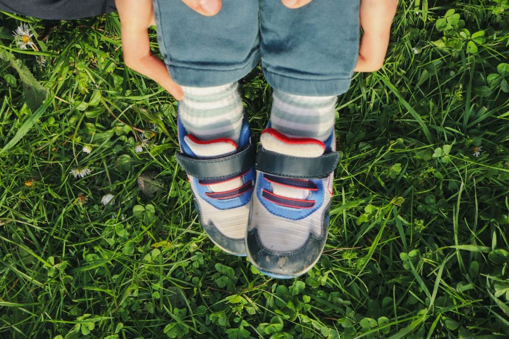 Kaki anak memakai sepatu di atas rumput